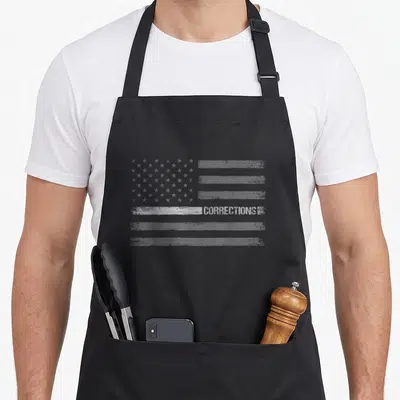 Flag line apron - Distressed grey USA flag with white stripe and CORRECTIONS text — shown on a black cotton canvas apron against a white background