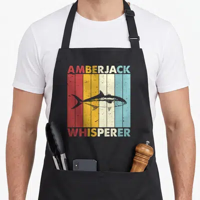 Amberjack fish apron - Grey amberjack fish over red orange yellow cream and blue vertical stripes with matching text — shown on a black cotton canvas apron against a white background