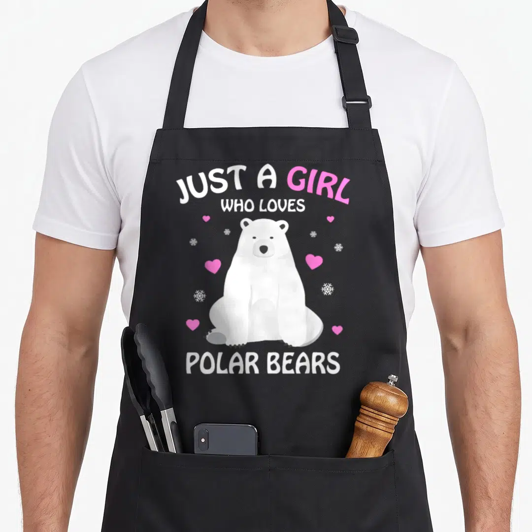 Vintage polar bear apron - White cartoon polar bear with pink hearts and snowflakes under Just A Girl Who Loves text — shown on a black cotton canvas apron against a white background