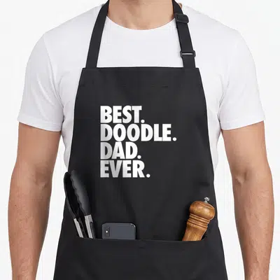 Retro doodle goldendoodle apron - White stacked text reading BEST. DOODLE. DAD. EVER. in bold block letters — shown on a black cotton canvas apron against a white background