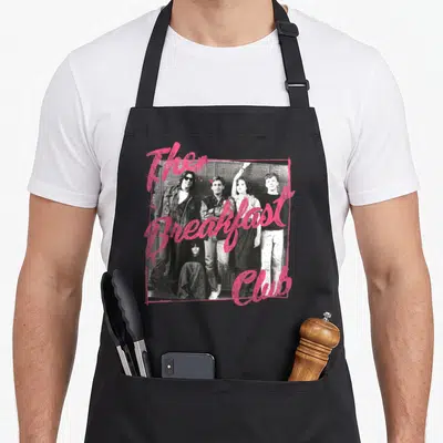 Photograph breakfast apron - Grayscale photo of five teens framed in pink with script text The Breakfast Club — shown on a black cotton canvas apron against a white background
