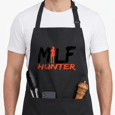 Womanizer hunter apron - MILF HUNTER text with orange-red female silhouette replacing the letter I in black brush font — shown on a black cotton canvas apron against a white background