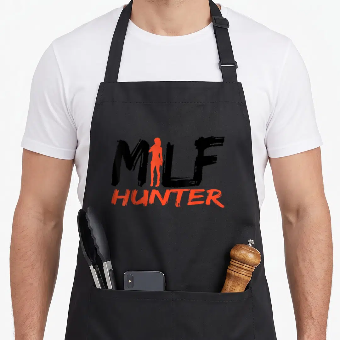 Womanizer hunter apron - MILF HUNTER text with orange-red female silhouette replacing the letter I in black brush font — shown on a black cotton canvas apron against a white background