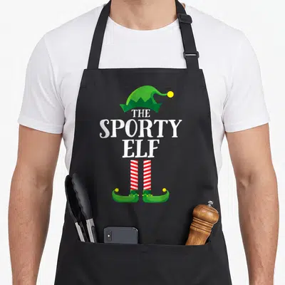 Sporty personalized family aprons - Green elf hat, white text, red and white striped legs, green shoes — shown on a black cotton canvas apron against a white background