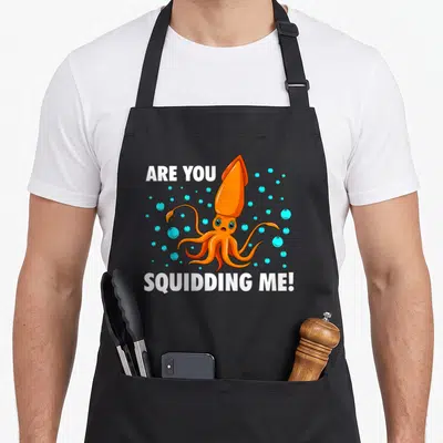 Zoologist fish apron - Orange cartoon squid with Are You Squidding Me text and blue bubbles — shown on a black cotton canvas apron against a white background