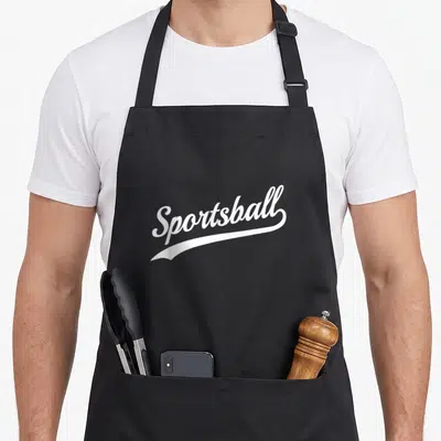 Sportsball sports team aprons - White script text reading Sportsball with an underline swoosh on a dark background — shown on a black cotton canvas apron against a white background
