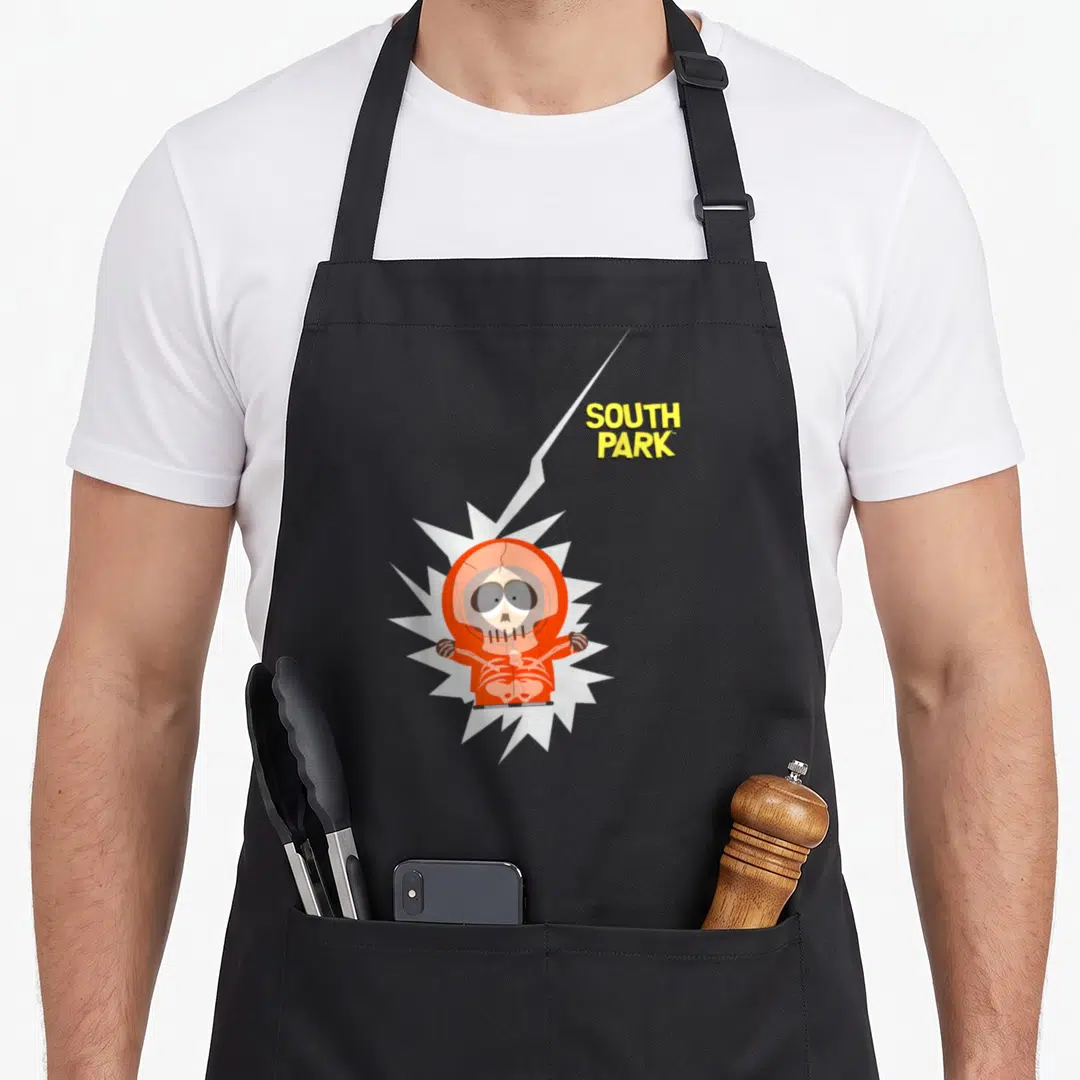 Lightening south apron - Cartoon character in orange suit inside white burst with yellow SOUTH PARK text and lightning — shown on a black cotton canvas apron against a white background