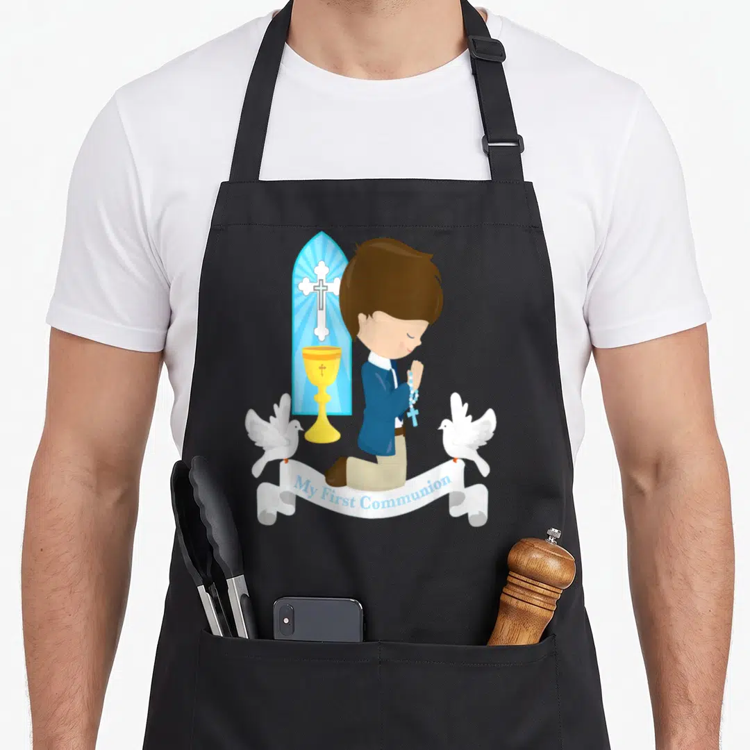 Hair communion aprons - Cartoon boy kneeling with chalice cross and two doves above My First Communion banner — shown on a black cotton canvas apron against a white background
