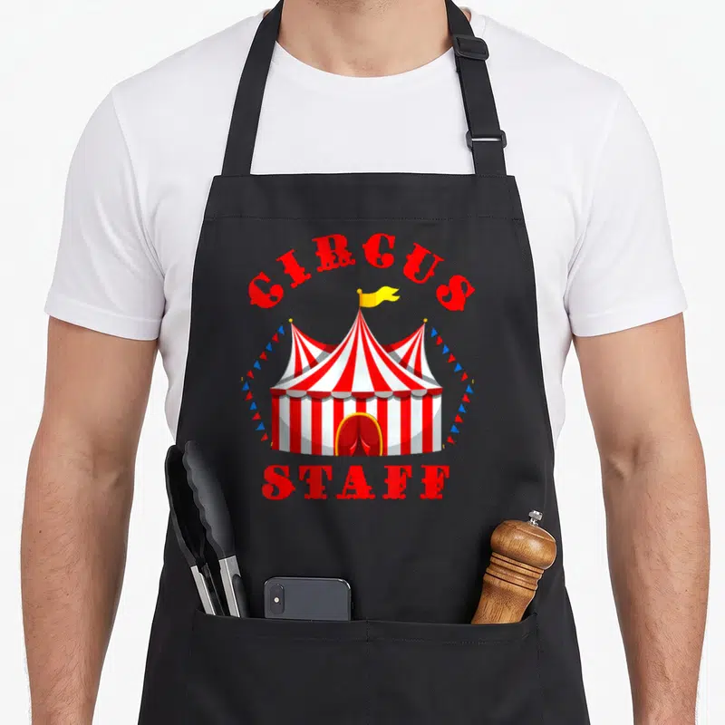 Staff birthday apron - Red and white striped circus tent with CIRCUS STAFF text and blue red bunting flags — shown on a black cotton canvas apron against a white background