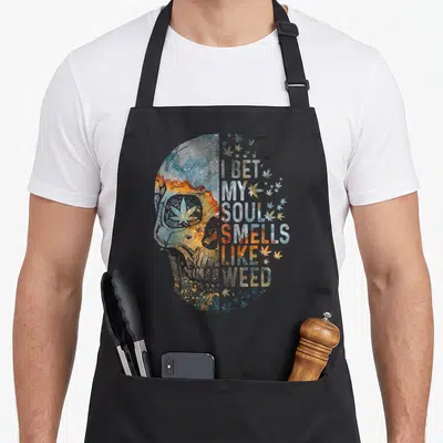 Bet skull apron - Galaxy skull profile and I BET MY SOUL SMELLS LIKE WEED text with scattered leaves — shown on a black cotton canvas apron against a white background