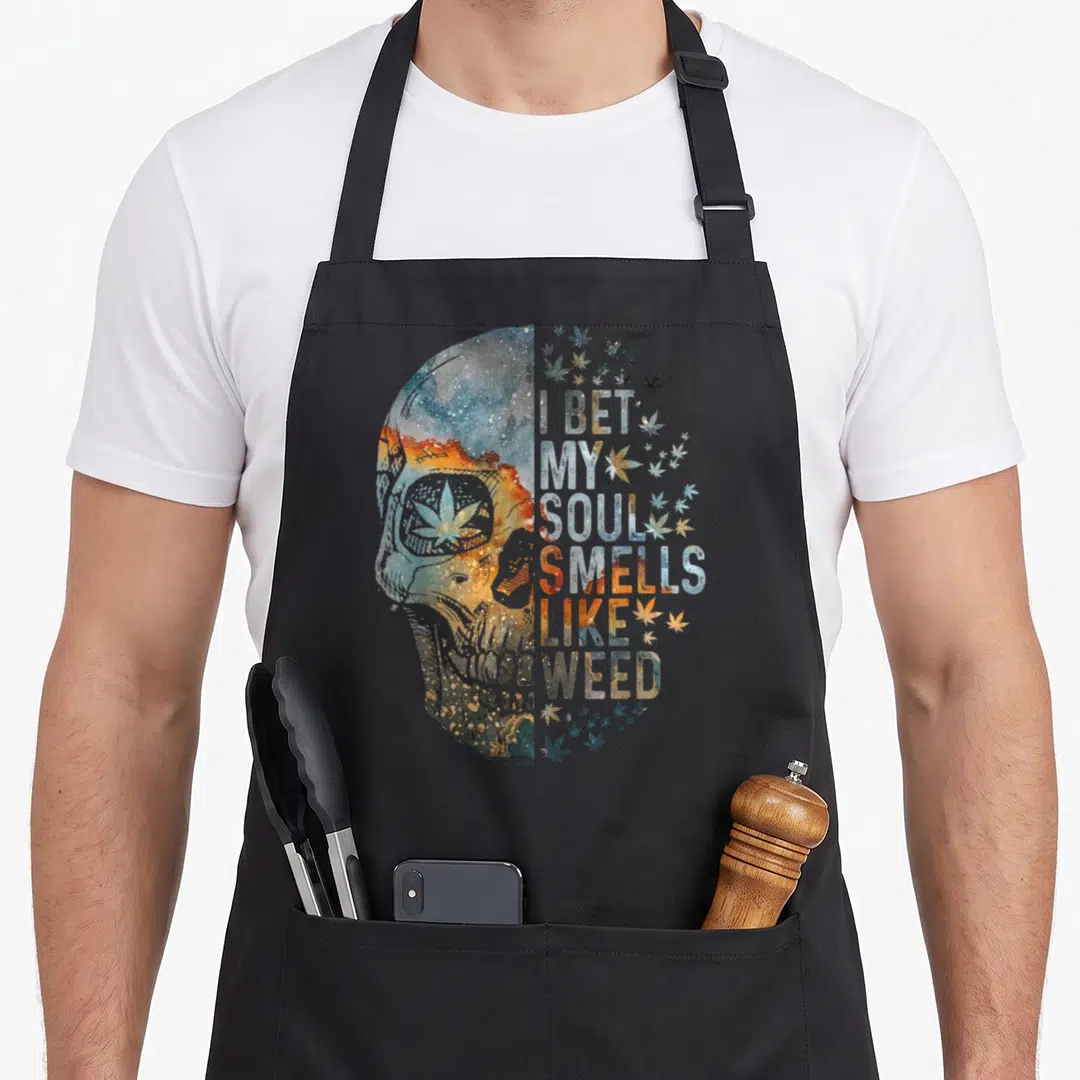 Bet skull apron - Galaxy skull profile and I BET MY SOUL SMELLS LIKE WEED text with scattered leaves — shown on a black cotton canvas apron against a white background