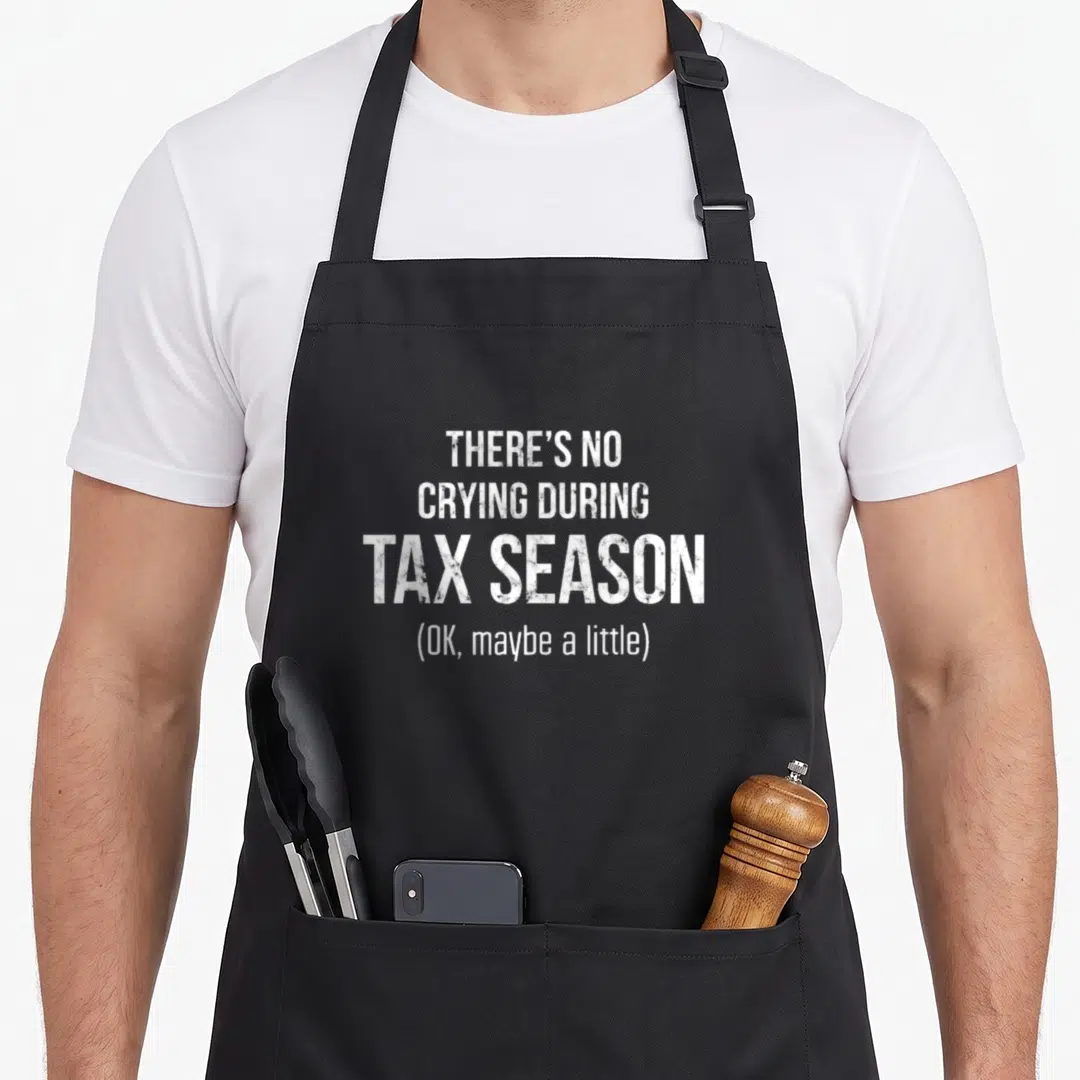 Crying tax apron - Distressed white text reading THERE'S NO CRYING DURING TAX SEASON OK maybe a little — shown on a black cotton canvas apron against a white background