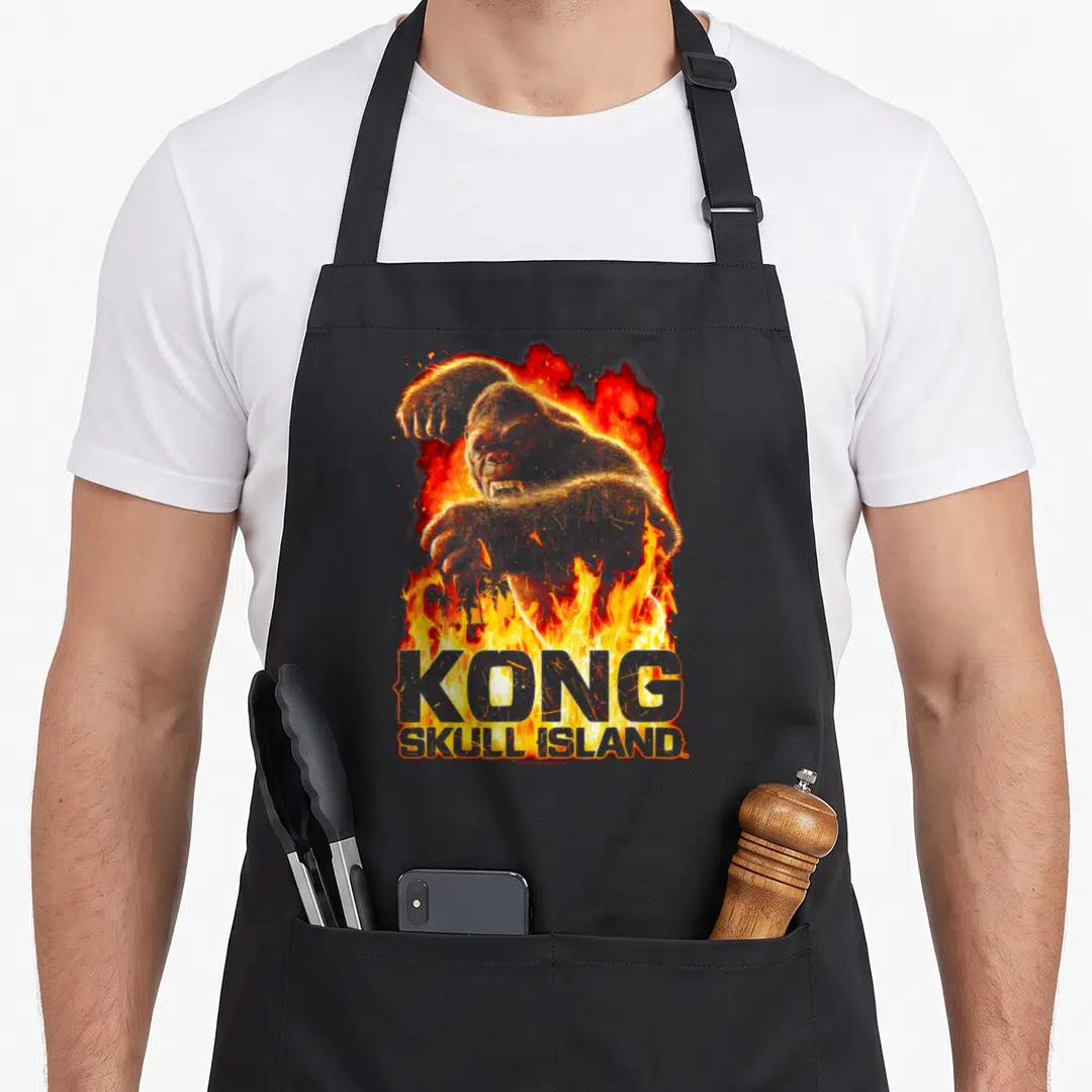 Kong kitchen island apron - Realistic gorilla above KONG SKULL ISLAND text surrounded by orange and red flames — shown on a black cotton canvas apron against a white background
