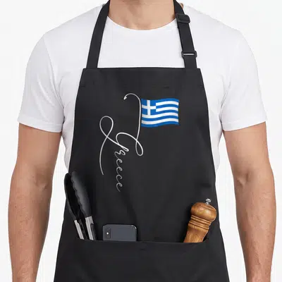 Family greek aprons - White script Greece forming a flagpole for a waving blue and white flag — shown on a black cotton canvas apron against a white background