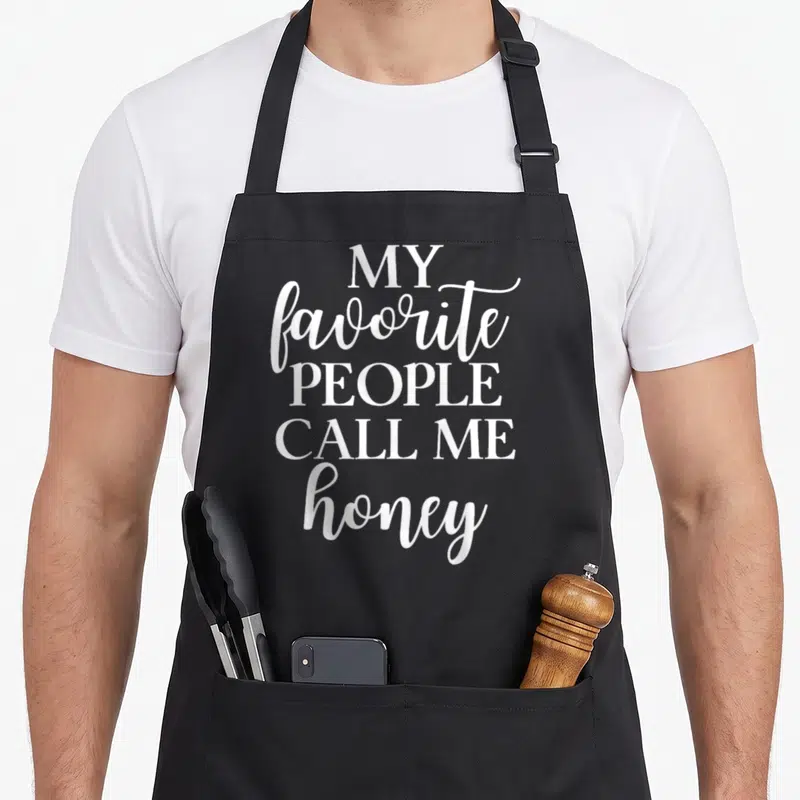 Call honey apron - White stacked text reading MY FAVORITE PEOPLE CALL ME HONEY — shown on a black cotton canvas apron against a white background