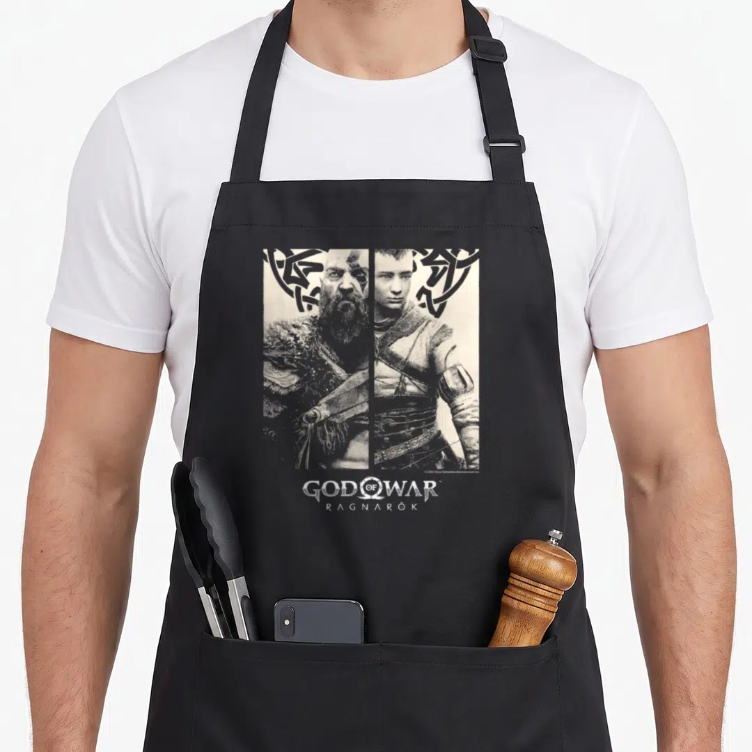 Contrast character aprons - Split portrait of Kratos and Atreus in grey and white with knotwork pattern and centered — shown on a black cotton canvas apron against a white background