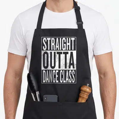 Straight ballet dance apron - Stacked white text reading straight outta dance class inside a distressed rectangular — shown on a black cotton canvas apron against a white background