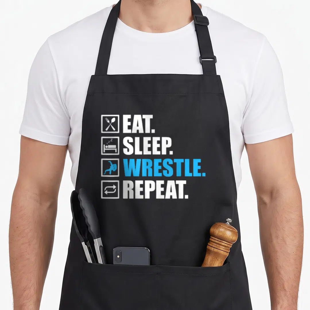 Athlete wrestling apron - Stacked EAT SLEEP WRESTLE REPEAT text with crossed fork spoon bed wrestler repeat icons — shown on a black cotton canvas apron against a white background