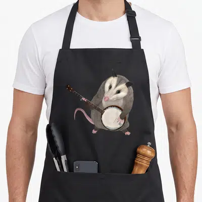 Possum world music apron - Realistic gray and white opossum holding a banjo with pink tail and paws — shown on a black cotton canvas apron against a white background