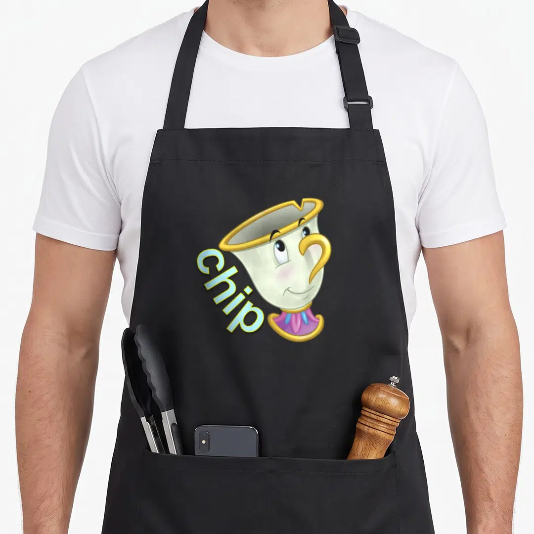 Chip face apron - Cartoon teacup with gold rim and blue text reading Chip — shown on a black cotton canvas apron against a white background