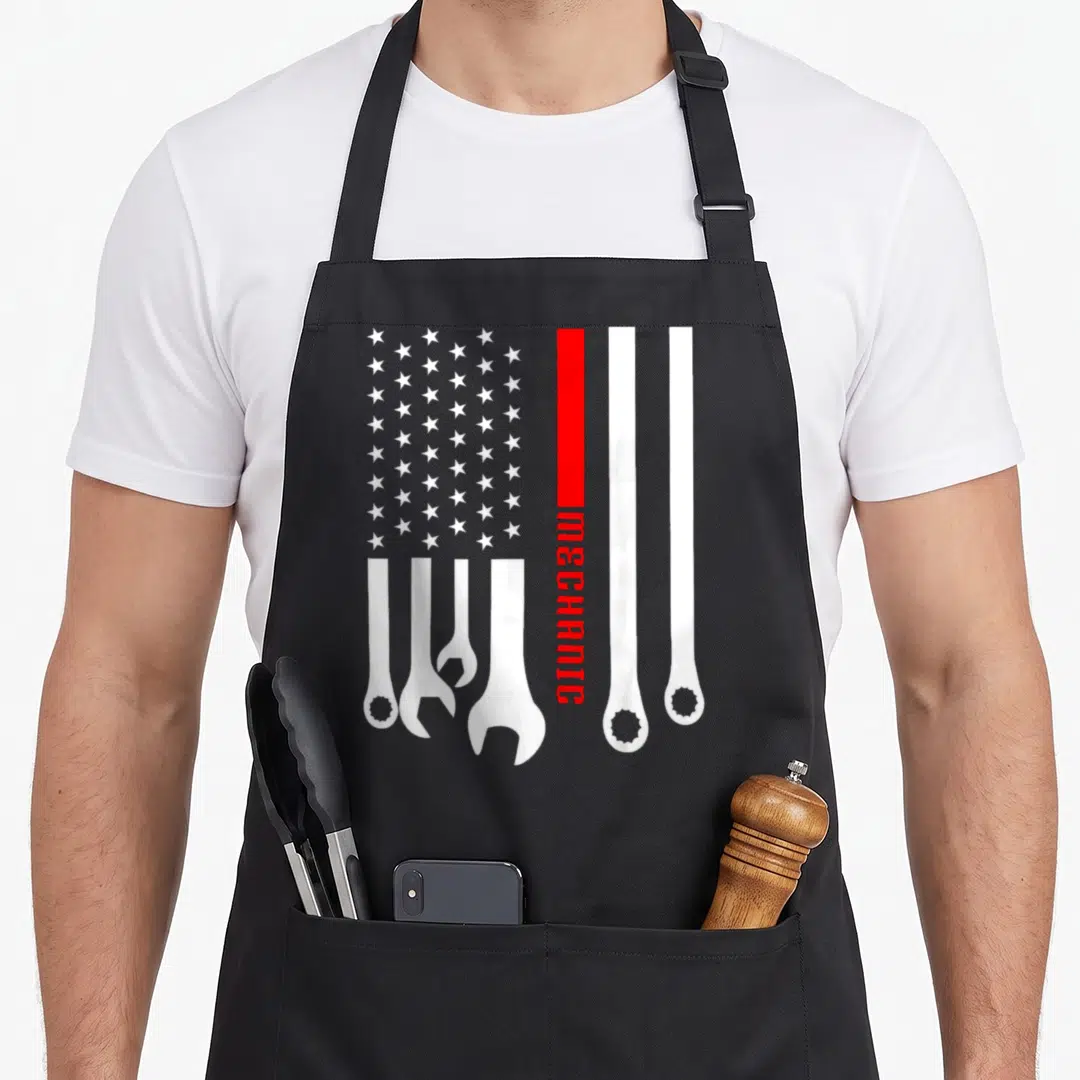 Engineer garage apron - Stylized US flag with white wrenches replacing stripes and vertical MECHANIC text on red stripe — shown on a black cotton canvas apron against a white background