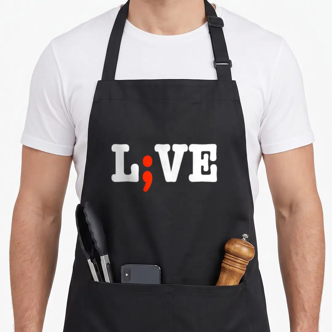 Live semi girl apron - L;VE text with red semicolon replacing letter I — shown on a black cotton canvas apron against a white background