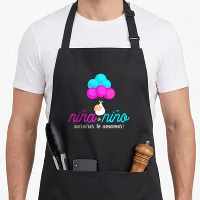 Latin apron or apron - Cartoon baby in swaddle lifted by pink and blue balloons above Spanish script — shown on a black cotton canvas apron against a white background