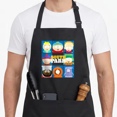 Gang south gate apron - 3x3 grid of South Park character faces surrounding yellow and white SOUTH PARK text on blue — shown on a black cotton canvas apron against a white background