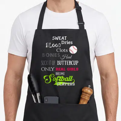Become softball apron - Stacked text reading SWEAT Dries BLOOD Clots BONES Heal SUCK IT UP BUTTERCUP ONLY REAL GIRLS — shown on a black cotton canvas apron against a white background