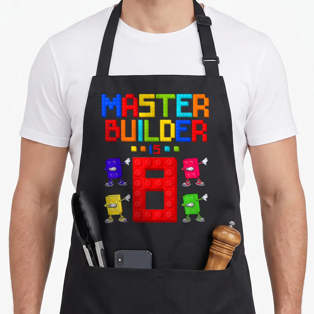 Yrs grill master apron - Colorful building block letters spelling Master Builder above a large red number 8 and four — shown on a black cotton canvas apron against a white background