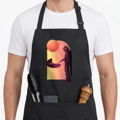 Epic novelty apron - Minimalist silhouette of helmeted figure and baby in cradle under a sun with rays in purple orange — shown on a black cotton canvas apron against a white background