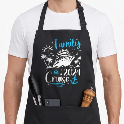 Trip memory apron - White cruise ship and blue text reading Family 2024 Cruise with anchor and palm trees — shown on a black cotton canvas apron against a white background