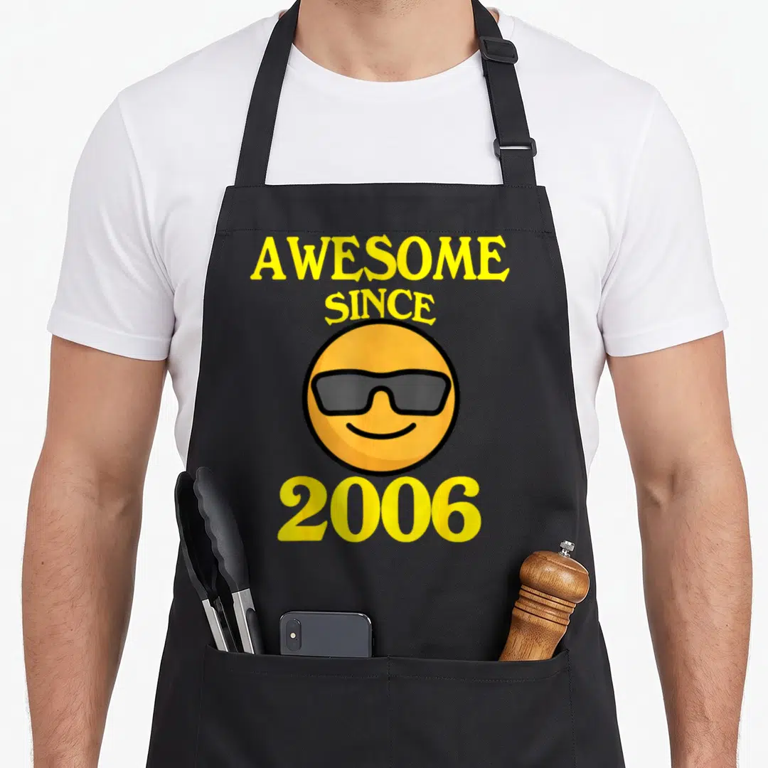 Cool 18th birthday apron - Awesome Since 2006 text surrounding a cartoon smiley face wearing grey sunglasses — shown on a black cotton canvas apron against a white background