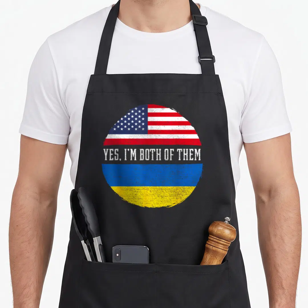 Ukraine heritage american flag apron - Circular split design of US and Ukraine flags with distressed white text Yes I'm — shown on a black cotton canvas apron against a white background