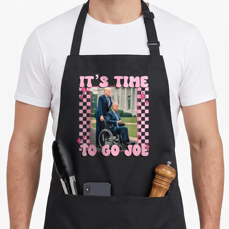Joe trump novelty apron - Pink checkered border around photo of Trump standing behind man in wheelchair with IT'S TIME — shown on a black cotton canvas apron against a white background