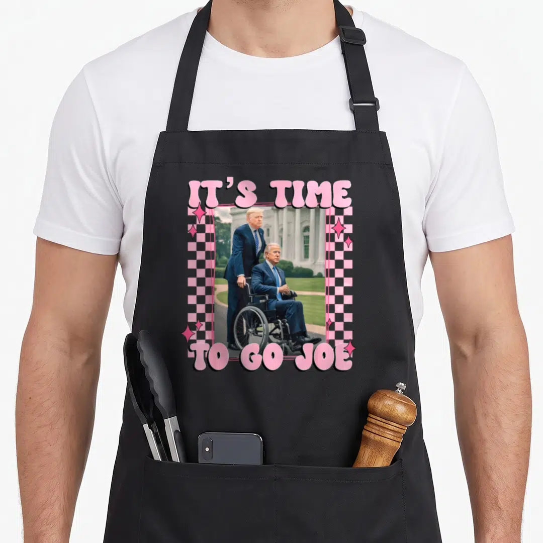 Joe trump novelty apron - Pink checkered border around photo of Trump standing behind man in wheelchair with IT'S TIME — shown on a black cotton canvas apron against a white background