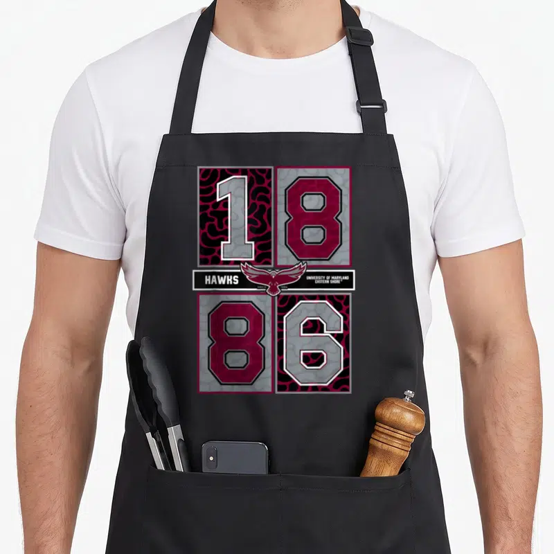 Concrete eastern shore apron - Hawks logo and 1886 numbers in maroon grey black white grid layout — shown on a black cotton canvas apron against a white background