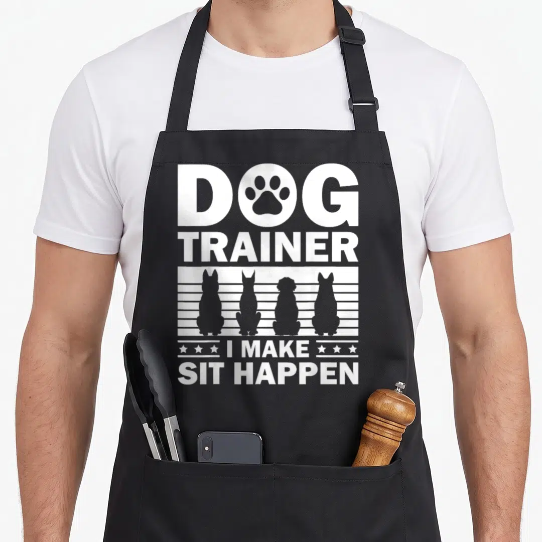 Agility dog training apron - White DOG TRAINER text with paw print and four sitting dog silhouettes on grey striped — shown on a black cotton canvas apron against a white background