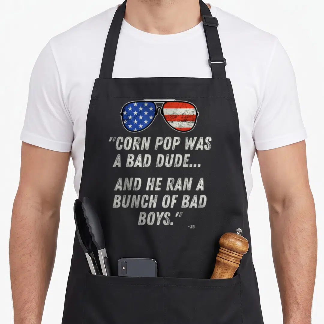 Pop dude apron - Sunglasses with US flag lenses above stacked quote text in distressed white font — shown on a black cotton canvas apron against a white background