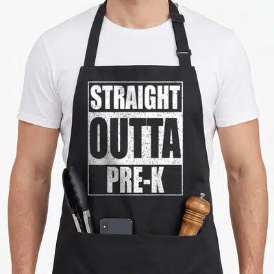 Outta preschool apron - White distressed text reading STRAIGHT OUTTA PRE-K inside a rectangular border — shown on a black cotton canvas apron against a white background