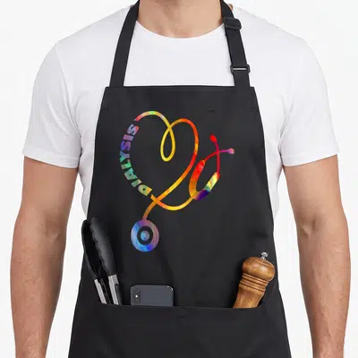 Technician nurse apron - Rainbow stethoscope heart shape with NURSE and DIALYSIS text integrated into the tubing — shown on a black cotton canvas apron against a white background
