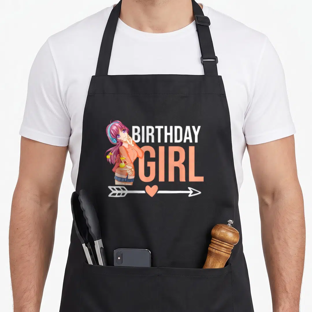 Cute manga anime mom apron - Anime girl with headphones next to BIRTHDAY GIRL text and arrow with heart in peach white — shown on a black cotton canvas apron against a white background