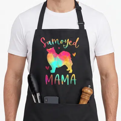 Samoyed mama dog apron - Colorful watercolor Samoyed silhouette with pink yellow blue orange hearts and Samoyed MAMA — shown on a black cotton canvas apron against a white background
