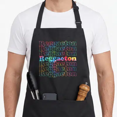 Reggaeton tie-dye apron - Seven stacked Reggaeton words in pink blue green yellow purple tie-dye font — shown on a black cotton canvas apron against a white background