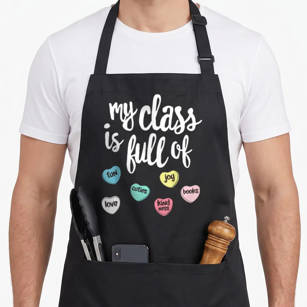 Class valentine's day apron - White script text above six colorful candy hearts with black words like fun and joy — shown on a black cotton canvas apron against a white background
