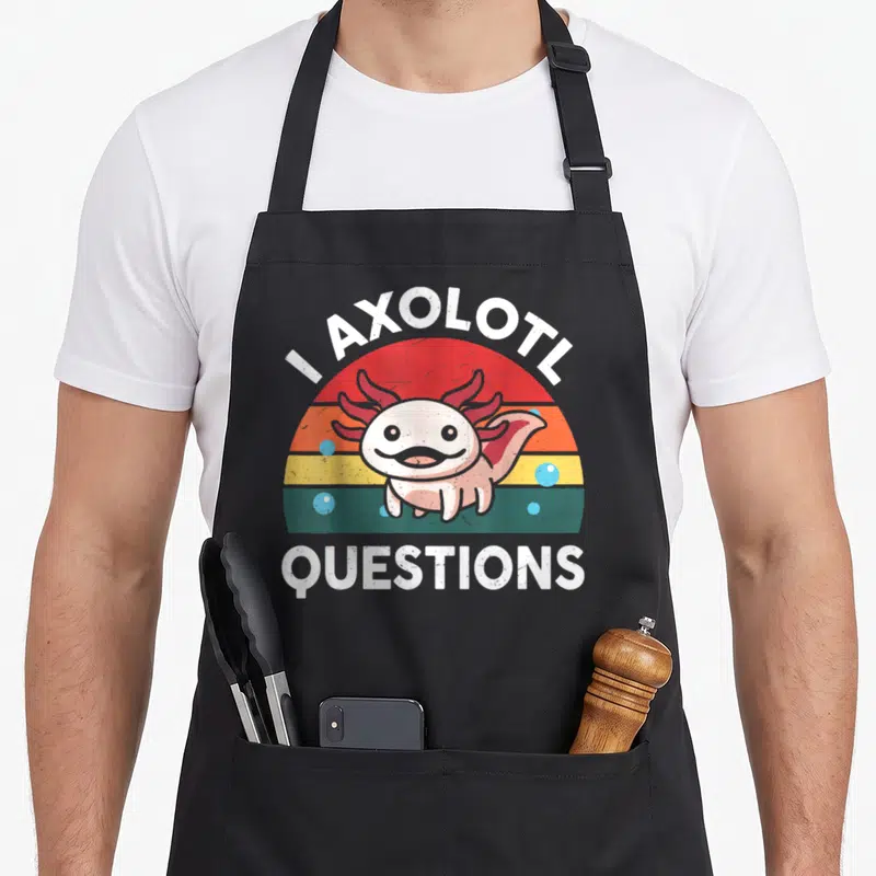 Funny question crazy axolotl man apron - Cartoon axolotl in front of striped sunset with I AXOLOTL QUESTIONS text — shown on a black cotton canvas apron against a white background
