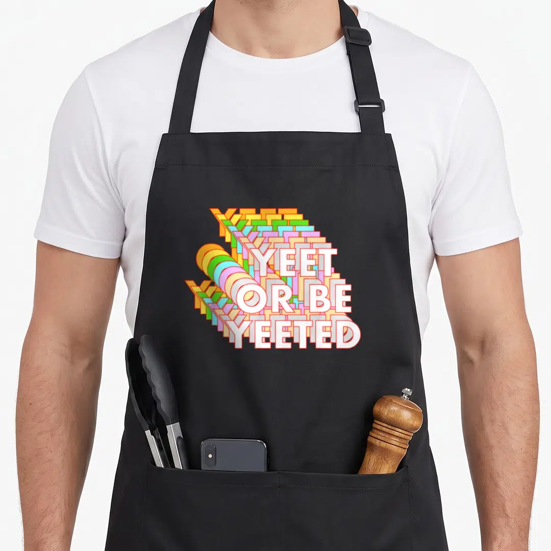 Yeet meme apron - Stacked white text Yeet Or Be Yeeted with colorful 3D echo effect on black background — shown on a black cotton canvas apron against a white background