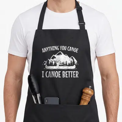 Anything canoe apron - White distressed text and paddler silhouette against mountains — shown on a black cotton canvas apron against a white background
