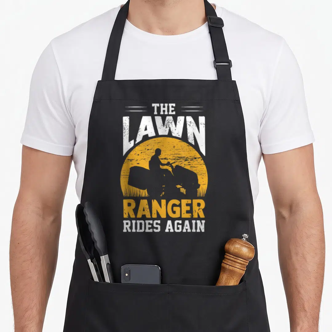 Landscaper rangers apron - Yellow sun with lawn tractor silhouette and distressed text THE LAWN RANGER RIDES AGAIN — shown on a black cotton canvas apron against a white background