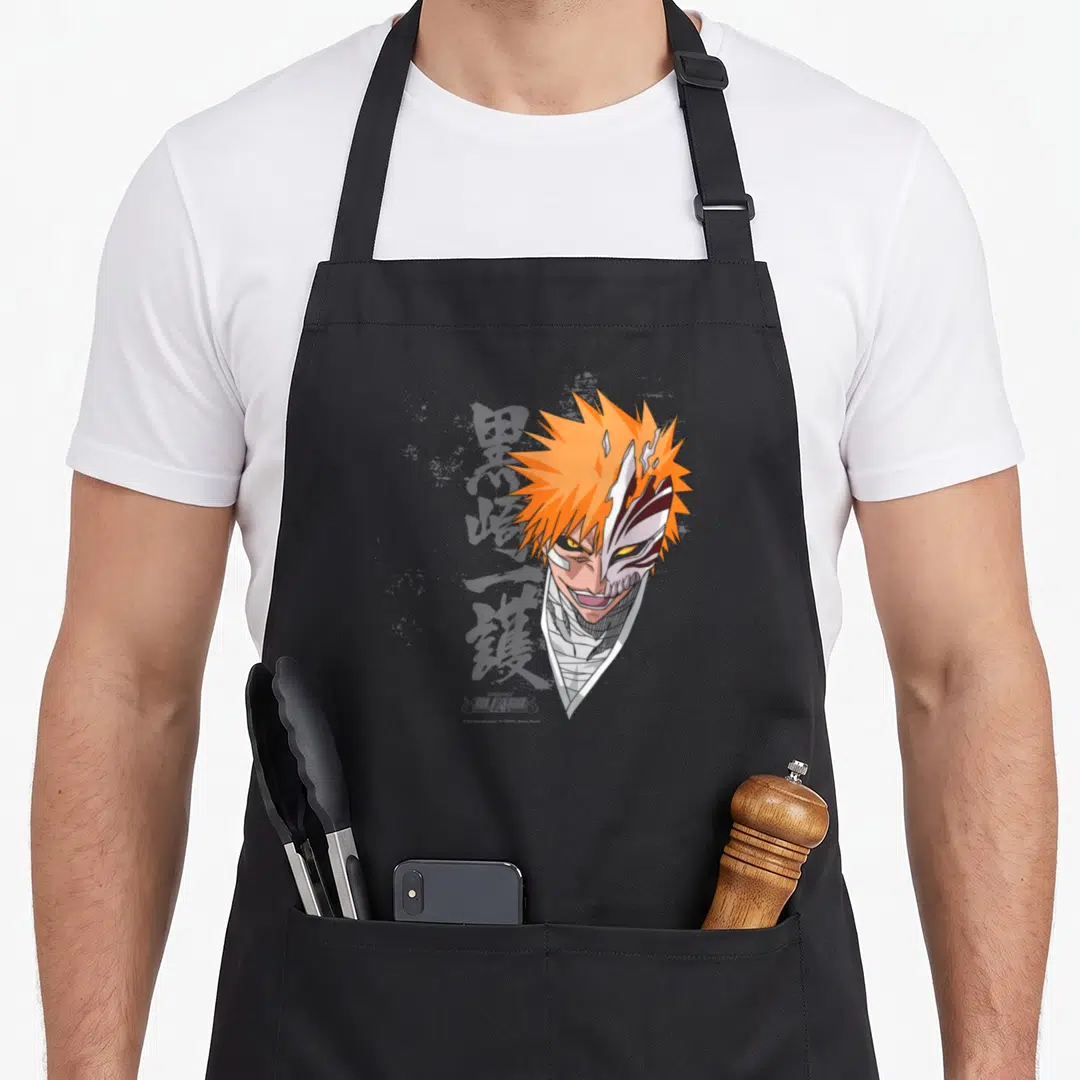 Ichigo anime apron - Orange spiky hair character with partial white mask and white neck bandages in cartoon style — shown on a black cotton canvas apron against a white background